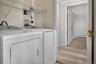 Dedicated laundry area featuring a washer and dryer set, tiled wall, and wire shelving