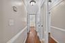 Hallway featuring wood-finish flooring, light-toned walls with chair rail molding, and white trim