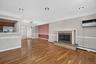 Living area featuring wood-finish flooring, a fireplace with a stone surround and hearth, recessed lighting, and crown molding