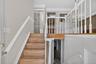 Split-level entry with wood-finish stairs, white baluster railing, and white crown molding