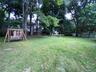 Spacious wide open private flat backyard with wooden swing and room for a pool or possibly even a pickleball court