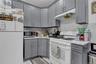 Kitchen featuring gray shaker-style cabinetry, white countertops, and a white marble-look tile backsplash
