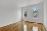 Room featuring two large windows, wood-finish flooring, white baseboards, and white painted walls