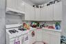Kitchen featuring white flat-panel cabinetry, white countertops, a white gas range with four burners, a white range hood, and a white and gray veined 