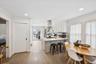Kitchen featuring crown molding, light wood finished floors, a peninsula, white cabinets, and island range hood