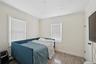 Bedroom with wood finished floors, ornamental molding, and a baseboard heating unit