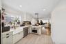 Kitchen with open floor plan, stainless steel appliances, crown molding, healthy amount of natural light, and light wood-style floors