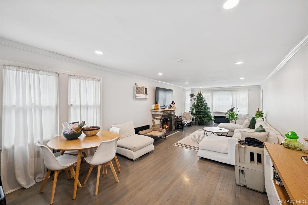 Living area with ornamental molding, dark wood-style floors, a stone fireplace, recessed lighting, and a wall mounted AC