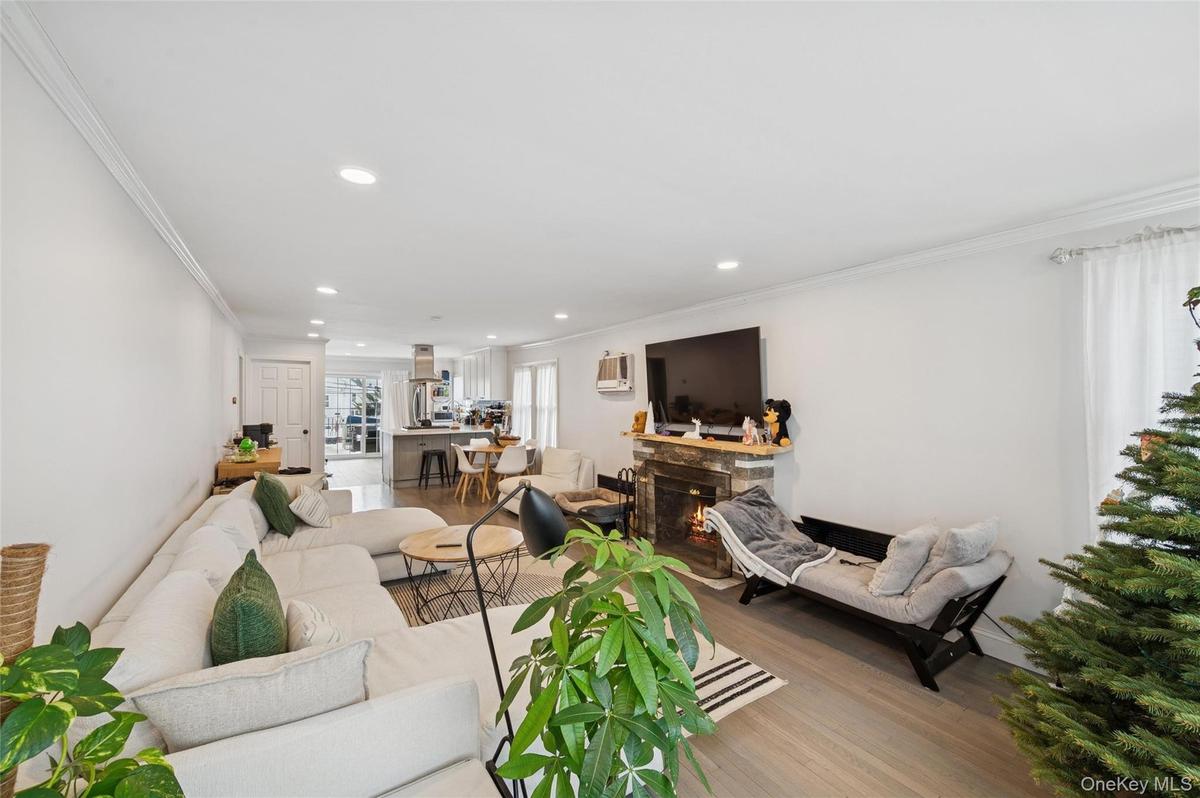 Living room featuring crown molding, recessed lighting, a fireplace, and wood finished floors