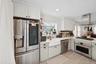 Kitchen with appliances with stainless steel finishes, ornamental molding, island exhaust hood, light wood-style floors, and white cabinets