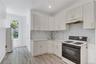 Kitchen featuring white cabinetry, light-toned countertops, a white subway tile backsplash, and wood-finish flooring