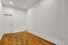 Room featuring wood-finish flooring, white walls, recessed lighting, and a white paneled door with a brass-toned knob