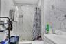 Bathroom featuring a walk-in shower with mosaic tile flooring, white marble-look wall tiling, and recessed lighting
