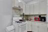 Kitchen featuring white cabinetry, a gas range, a stainless steel sink with a gooseneck faucet, light-toned countertops, and a patterned backsplash