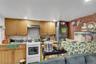 Kitchen area featuring wood cabinetry, a white electric range, a stainless steel sink, and a refrigerator with an overhead microwave