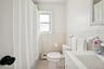 Full bath featuring a shower with shower curtain, vanity, a baseboard radiator, light tile patterned floors, and tile walls