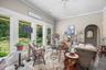 A wonderful sun room/den with a wall of windows overlooks lovely gardens