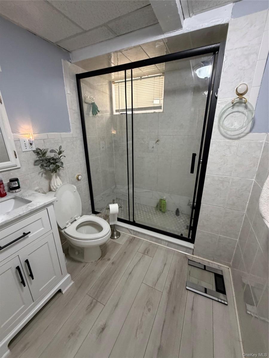 Contemporary bathroom featuring a glass-enclosed shower with a black frame and tiled walls