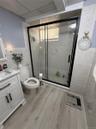 Contemporary bathroom featuring a glass-enclosed shower with a black frame and tiled walls