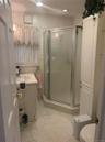 Tiled bathroom featuring a corner shower with frosted glass doors, white vanity with integrated sink, and recessed lighting