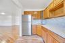Kitchen featuring a stainless steel refrigerator, wood-finish cabinetry, white countertops, and a white tile backsplash