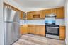 Kitchen featuring wood-finish cabinetry, stainless steel appliances, white countertops, and a full tile backsplash