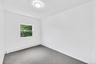 Room featuring a single window, grey carpet, white walls, and a ceiling-mounted light fixture
