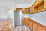 Kitchen area with natural wood cabinetry and a stainless steel refrigerator