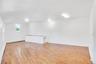Spacious room featuring wood-finish flooring, white walls, and multiple windows