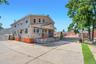 Expansive concrete driveway with a two-story residence featuring light siding and stucco accents