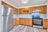 Modern kitchen featuring light wood cabinetry, stainless steel appliances, white countertops, and a white tile backsplash