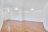 Spacious room featuring wood-finish flooring, white walls, and contemporary flush-mount lighting fixtures