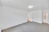 Spacious room featuring neutral carpeting, white walls, and a modern ceiling light fixture