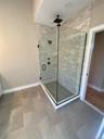 Floor-to-ceiling tile and a sleek glass enclosure transform the walk-in shower into a luxurious spa-like retreat.