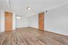 Spacious room featuring wood-finish flooring, white walls, and a recessed ceiling light