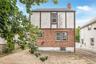 Brick and stucco exterior featuring multiple windows and a chimney