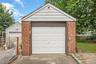 Brick garage featuring a white panel garage door and white siding gable