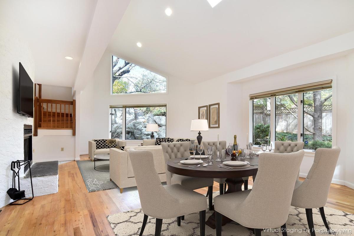 Virtually staged Living/Dining area with high vaulted ceiling, light wood flooring, recessed lighting, and a fireplace