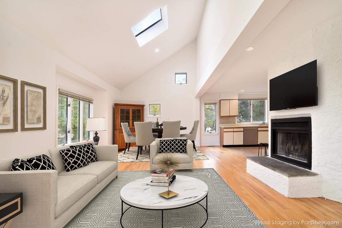 Virtually stagedLiving area with high vaulted ceiling, a skylight, light wood flooring, recessed lighting, and a fireplace with raised hearth