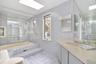 Primary Bathroom featuring tile walls, a skylight, light tile patterned floors, and vanity
