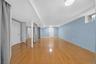 Spacious open floor plan showcasing gleaming wood-finish flooring, soft blue accent walls, and abundant natural light from recessed ceiling fixtures
