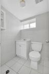 Bright and functional bathroom featuring white subway tile walls, ceramic tile flooring, a white vanity cabinet with dual doors and hardware, and a st