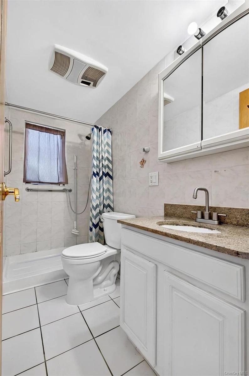 White vanity with a stone-finish countertop and undermount sink