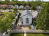 Brick Colonial residence showcasing a gabled roofline, arched entryway with transom windows, and a professionally landscaped front courtyard framed by