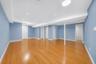 Spacious room featuring wood-finish flooring, recessed lighting, and multiple doors with white trim