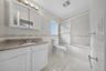 Spa-inspired primary bathroom featuring a white vanity with granite countertop, medicine cabinet with mirrored glass doors, ceramic tile flooring, and