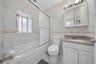 Tiled bathroom featuring a built-in bathtub with sliding glass doors, white vanity with a light-colored countertop, and a wall-mounted medicine cabine