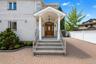 Brick exterior featuring a covered entry, wood-finish front door, and a paved driveway