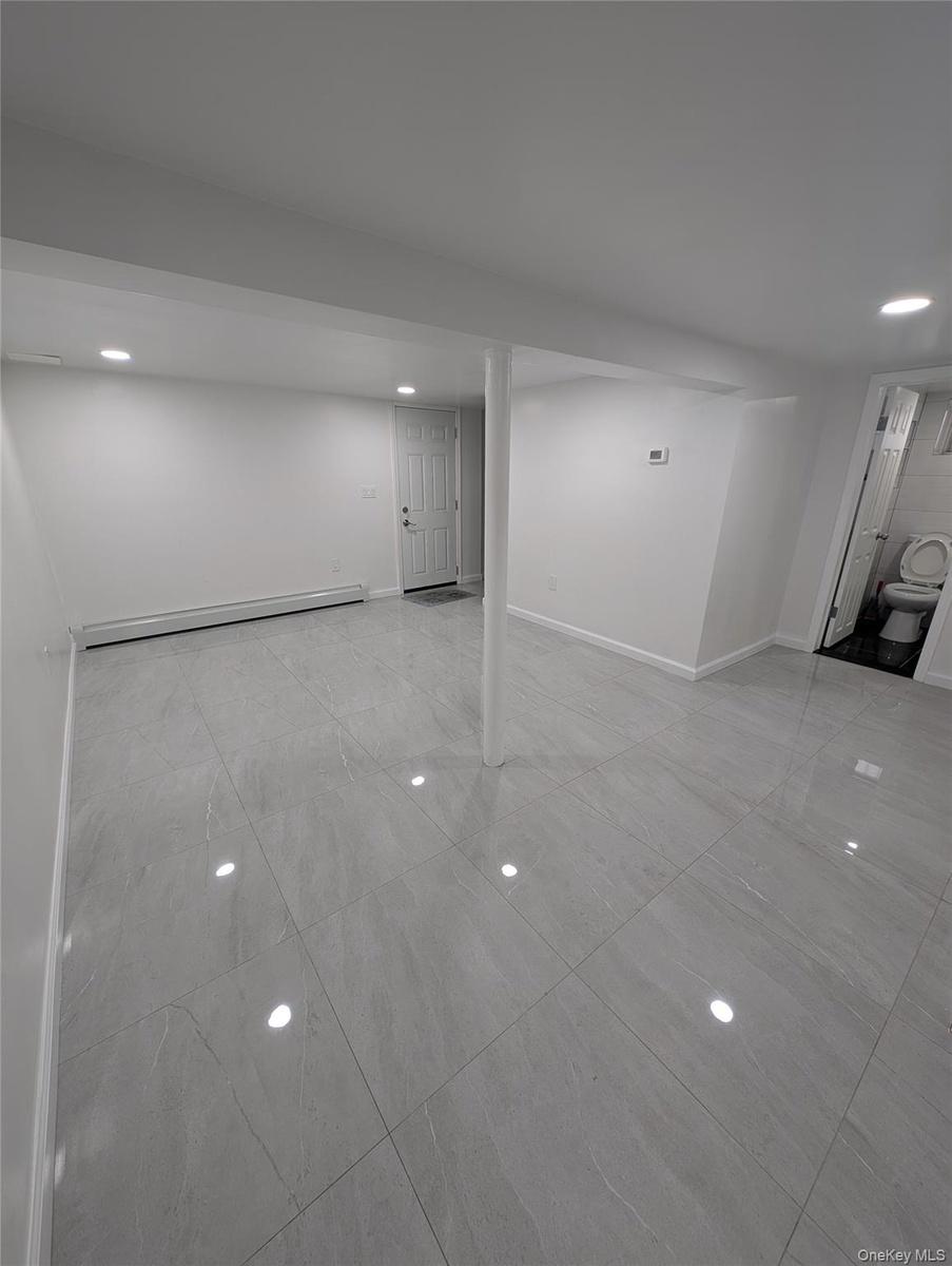 Basement with a baseboard radiator, recessed lighting, marble finish floor, and baseboards
