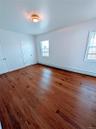 Unfurnished bedroom featuring a baseboard radiator, wood finished floors, and baseboards